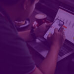 Profissional analisando métricas de tráfego pago em laptop e smartphone, com gráficos de performance e dados de campanhas digitais.